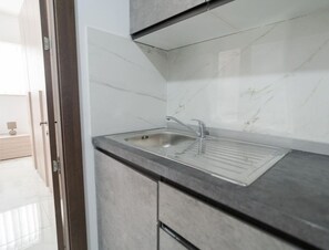 A modern kitchen with a stainless steel sink, grey countertops, and white marble backsplash. - Sleek & Simple comfy Studio near Griza Promenade! (Gżira)