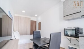 Ein modernes Hotelzimmer mit einem Bett, einem Schreibtisch, einem Stuhl, einer Mikrowelle und einem Mülleimer.