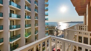 A high-rise building with multiple balconies overlooking a coastal area.