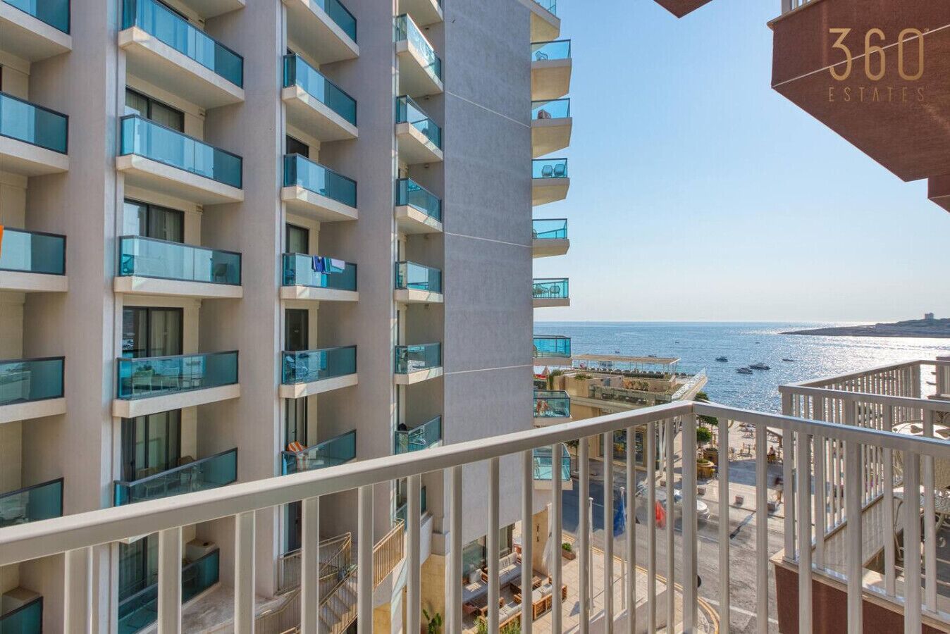 A high-rise building with multiple balconies overlooking a beach.
