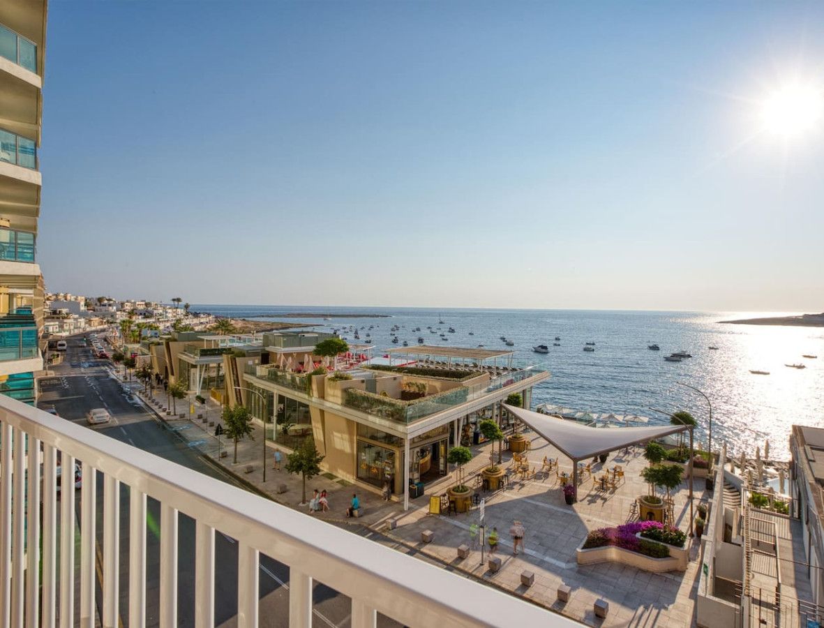 A coastal hotel with a rooftop bar, outdoor seating, and a view of the sea.