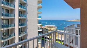 A high-rise building with multiple balconies overlooking a beach.