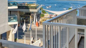 A high-rise building with multiple balconies overlooking a coastal area with boats and a beach. - Stylish 2BR Stay with Balcony Sunsets & Sea Views! (St. Paul`s Bay)