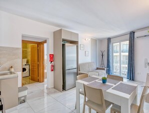 A modern apartment with a dining area, kitchen, and a balcony with a view.