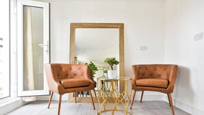 A room with two brown leather armchairs, a small round table, and a large mirror with a wooden frame.