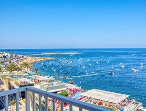A coastal view with a marina, beach, and buildings with balconies overlooking the sea.