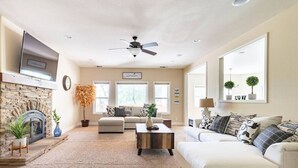 A living room with a fireplace, sofa, coffee table, and a TV mounted on the wall.