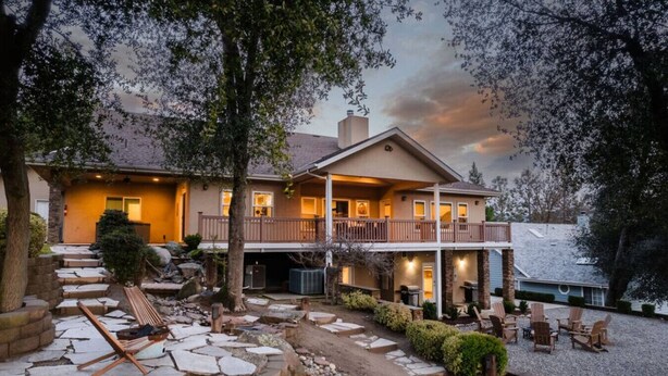 A two-story house with a covered patio area, stone steps leading to the entrance, and outdoor seating.