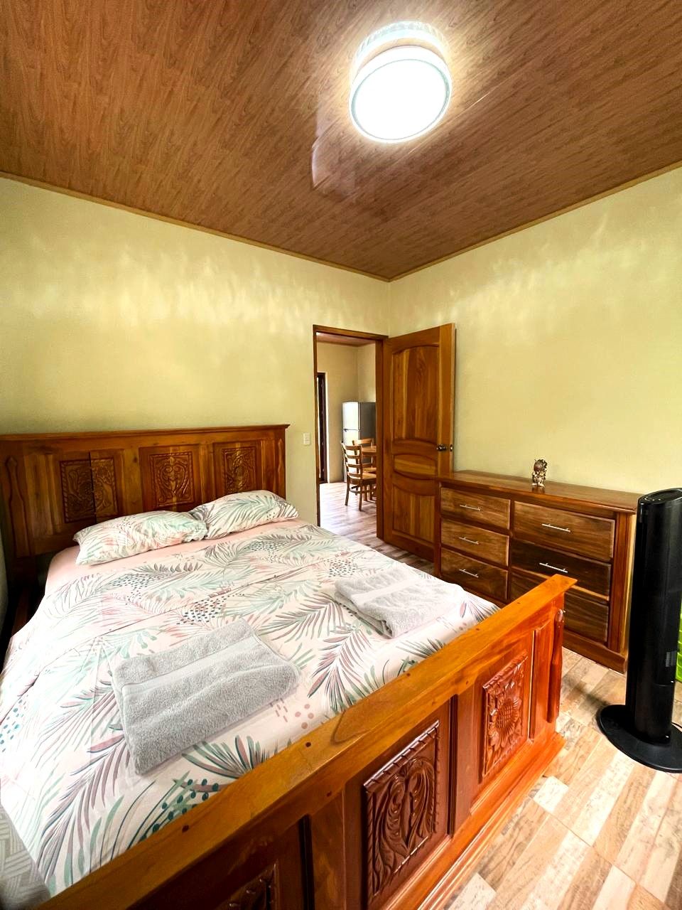 A bedroom with a wooden bed, a dresser, and a ceiling light.