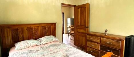 A bedroom with a wooden bed, a dresser, and a ceiling light.