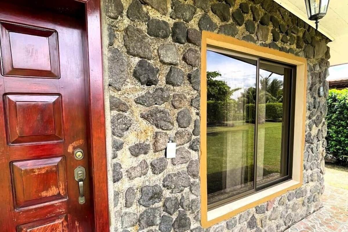 Une façade en pierre avec une porte en bois et une grande fenêtre.