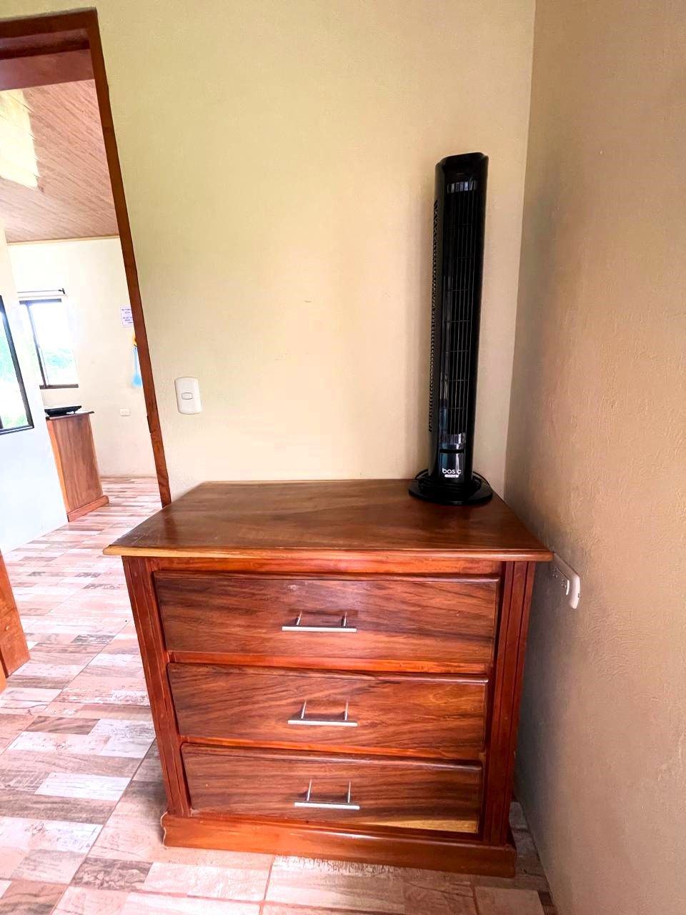A wooden cabinet with three drawers and a black object on top.