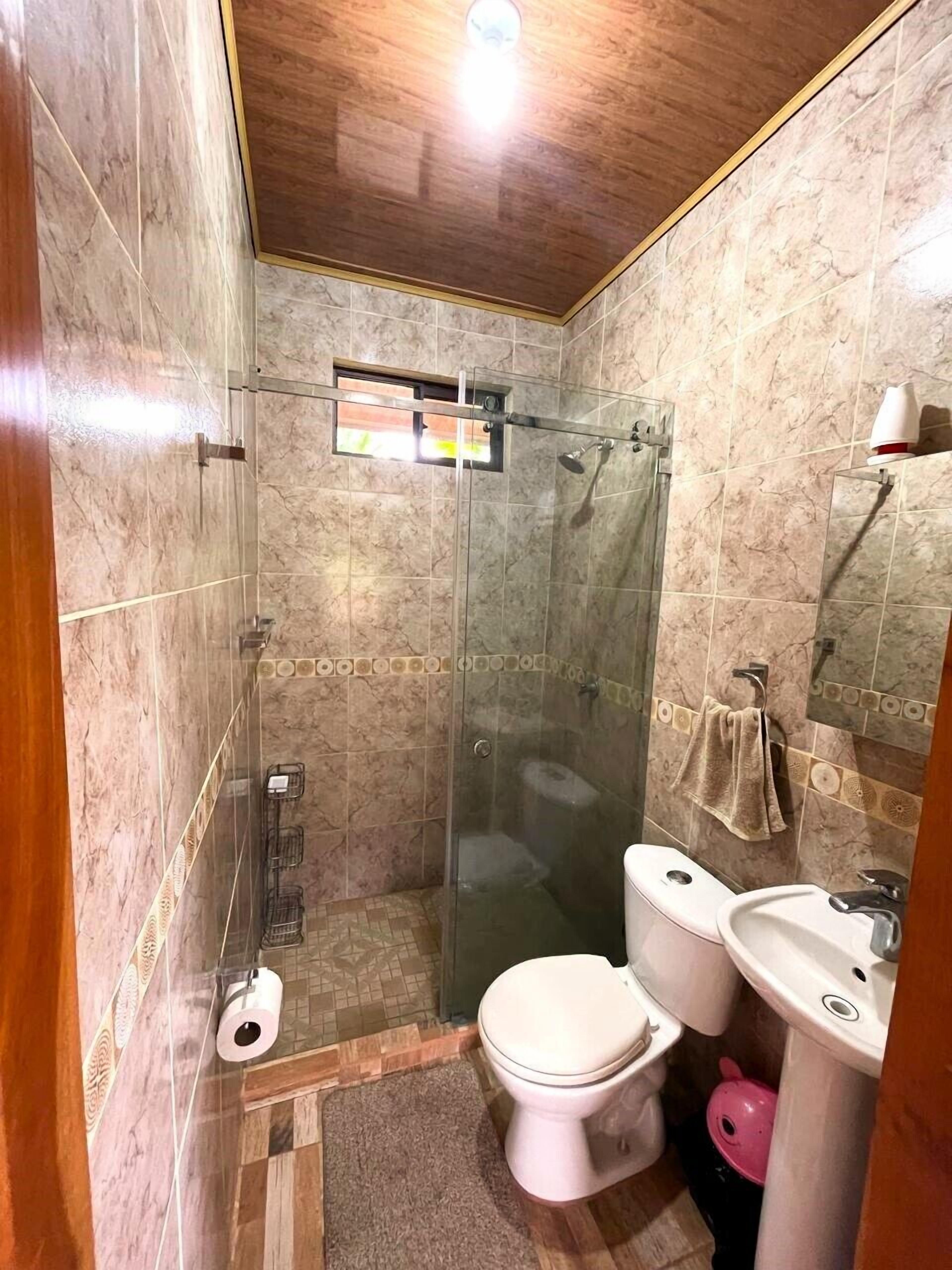 A bathroom with a glass-enclosed shower, a toilet, and a sink.