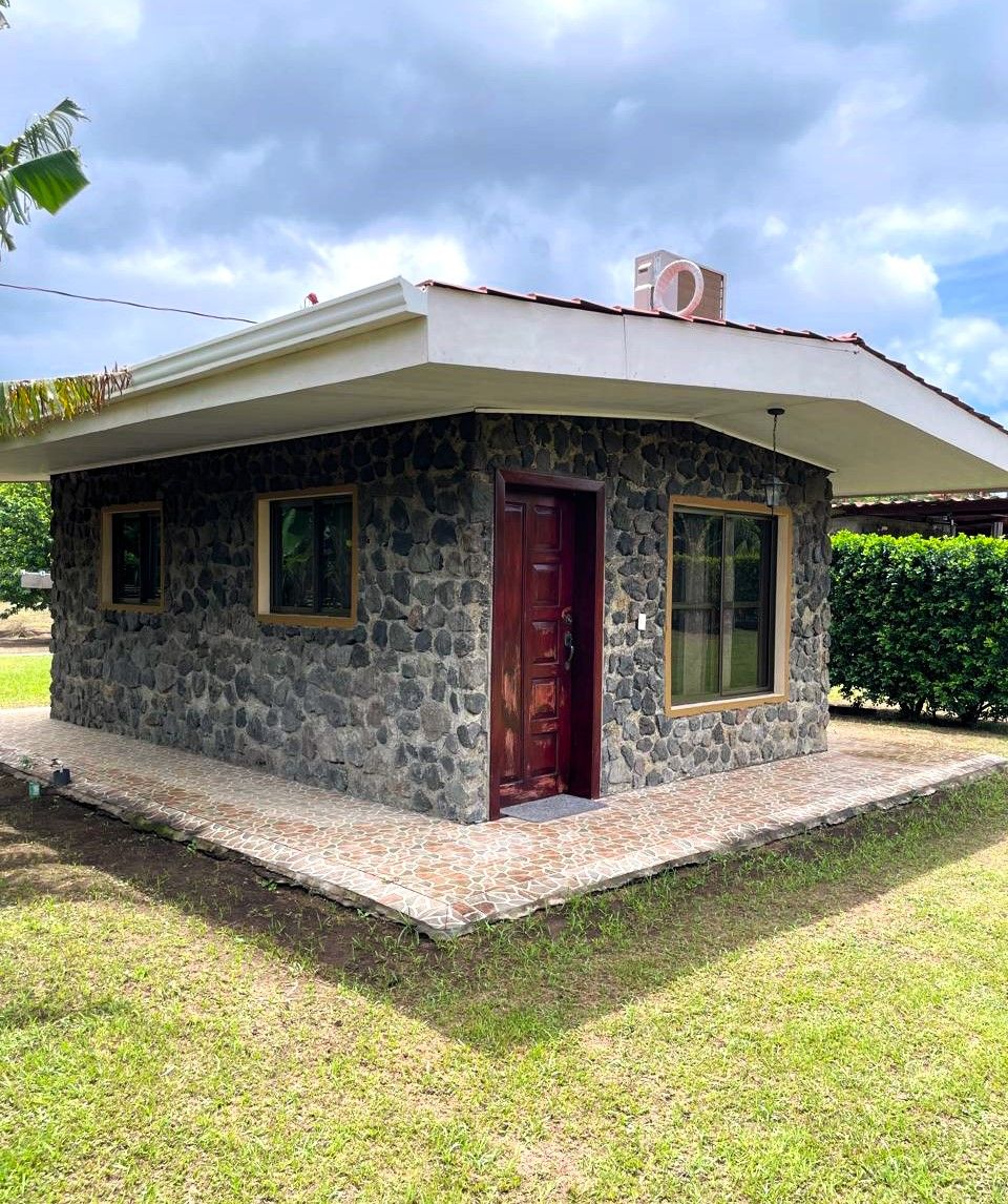 A small stone house with a red door, a covered porch, and a clear sky.