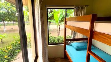 Une chambre avec un lit superposé, une grande fenêtre et une vue sur la verdure.