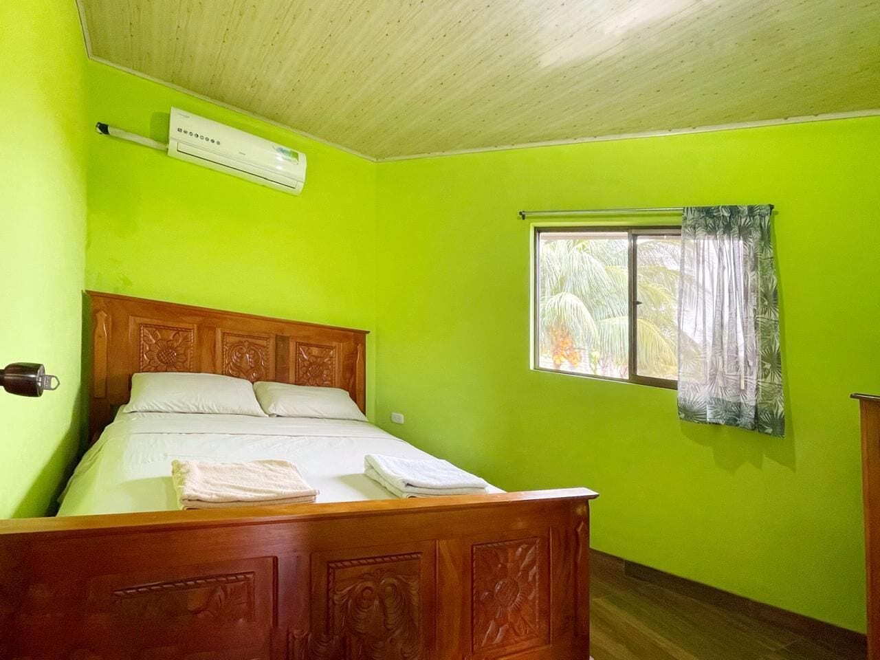 A room with a wooden bed, a window with curtains, and a ceiling fan.
