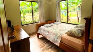 Un dormitorio con una cama de madera, un aparador de madera y una ventana con cortinas.