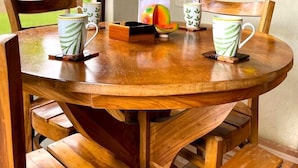 Una mesa redonda de madera con dos tazas y un frutero.