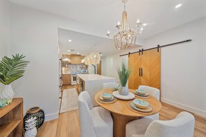 A modern dining area with a round table, white chairs, and a chandelier.