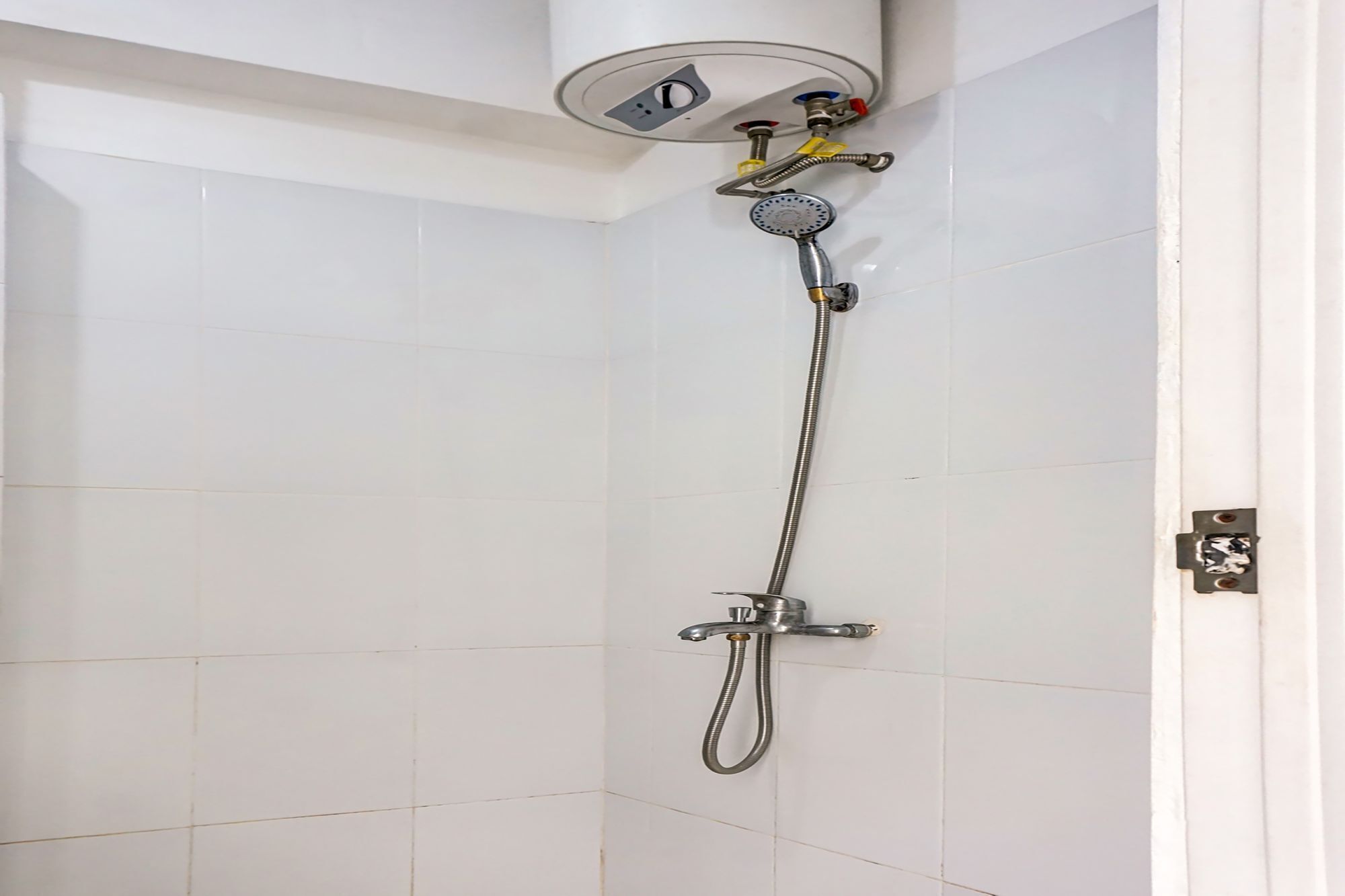 Ducha con cabezal de ducha de mano y cabezal de ducha fijo, ambos instalados en una pared con azulejos blancos.