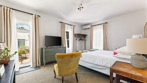 Una camera d'albergo con un letto, una televisione, una scrivania, una sedia e una finestra con tende.