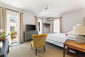 Ein Hotelzimmer mit einem Bett, einem Fernseher, einem Schreibtisch, einem Stuhl und einem fensterbepflanzten Fenster.