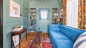 Un soggiorno accogliente con un divano blu, un tavolino in legno e librerie piene di libri.
