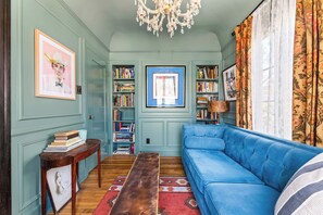 Ein gemütliches Wohnzimmer mit einem blauen Sofa, einem Holztisch und Bücherregalen voller Bücher.