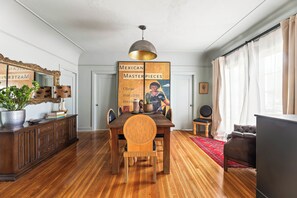 A dining area with a wooden table, chairs, a chandelier, and a poster on the wall.
