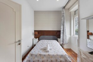 Un dormitorio con cama, lámparas de noche, una ventana y una puerta.