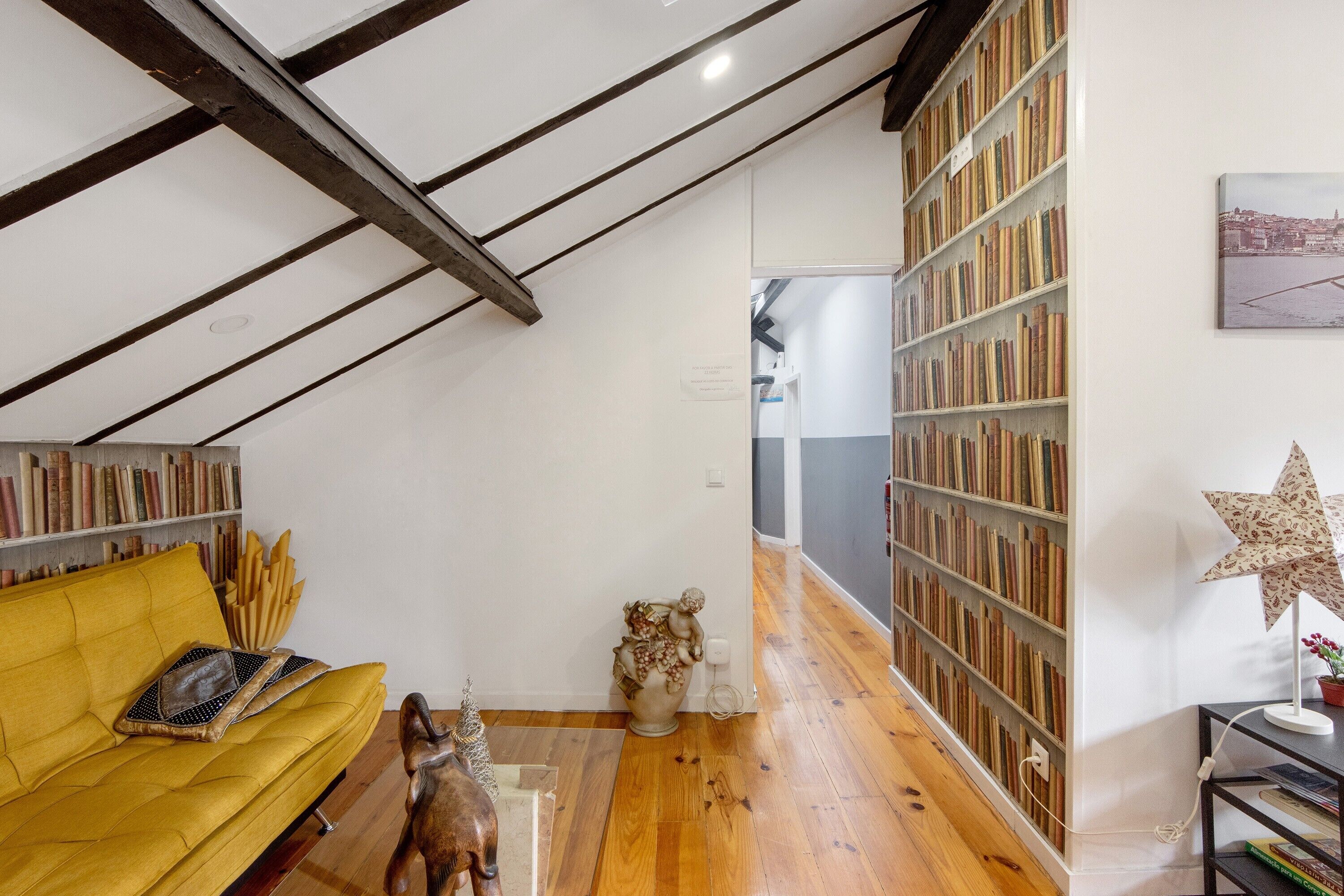 Une pièce avec un canapé jaune, une bibliothèque, un plancher en bois et une lampe en forme d’étoile.