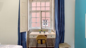Ein Zimmer mit Schreibtisch, Stuhl und einem fenster mit Vorhängen.