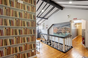 Una biblioteca con estanterías, una escalera y un cuadro de un puente.