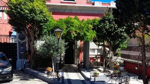 A stone-paved street leading to a building with a red facade and a white door.