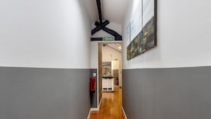 A hallway with a wooden floor, a fire extinguisher, and a sign indicating the direction to the exit. - Room 'K' with Shared Garden and Wi-Fi (Porto)