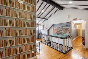 Een bibliotheek met boekenkasten, een trap en een schilderij van een brug.