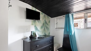 A room with a TV mounted on the wall, a dresser with drawers, a chair, and a window with a curtain. - Room 'K' with Shared Garden and Wi-Fi (Porto)
