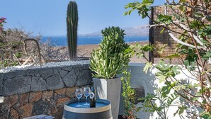 A stone wall, a cactus, a barrel with glasses and a bottle, and a view of the sea. - Holiday Villa 'Dafmir' with Sea Views, Wi-Fi and Air Conditioning (Tías)