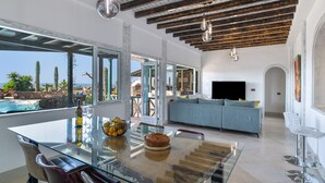 A modern interior with a glass dining table, a sofa, and a pool view. - Holiday Villa 'Dafmir' with Sea Views, Wi-Fi and Air Conditioning (Tías)