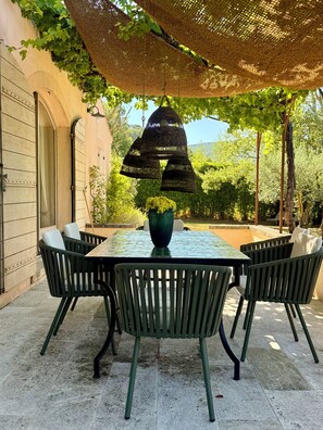 Un patio al aire libre con una mesa redonda, sillas y una lámpara colgante.
