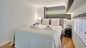 Una habitación de hotel moderna con una cama grande, mesitas de noche y una estantería empotrada.