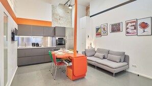 Una cocina moderna con gabinetes grises y una zona de comedor con una mesa y sillas rojas.