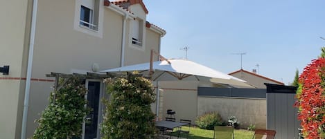 A residential building with a patio area featuring outdoor furniture and a pergola.