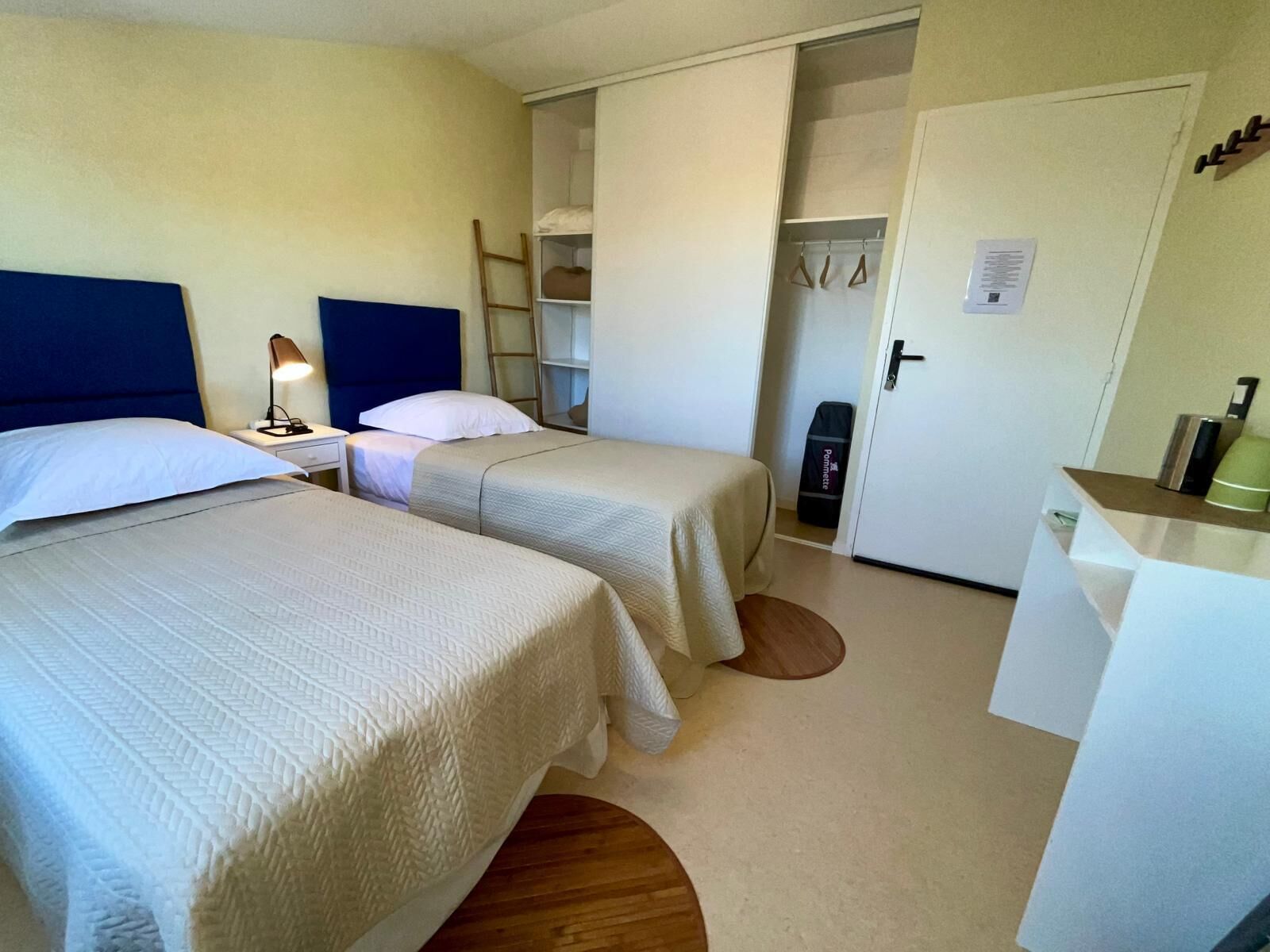Une chambre avec deux lits, une table de chevet, un bureau et une armoire.