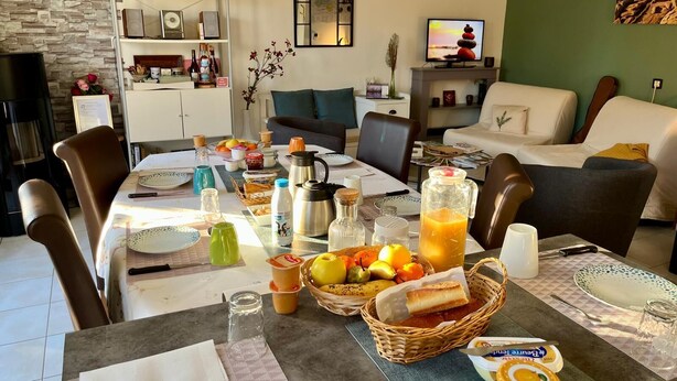 Un comedor con una mesa preparada para el desayuno, que incluye frutas, pan y bebidas.