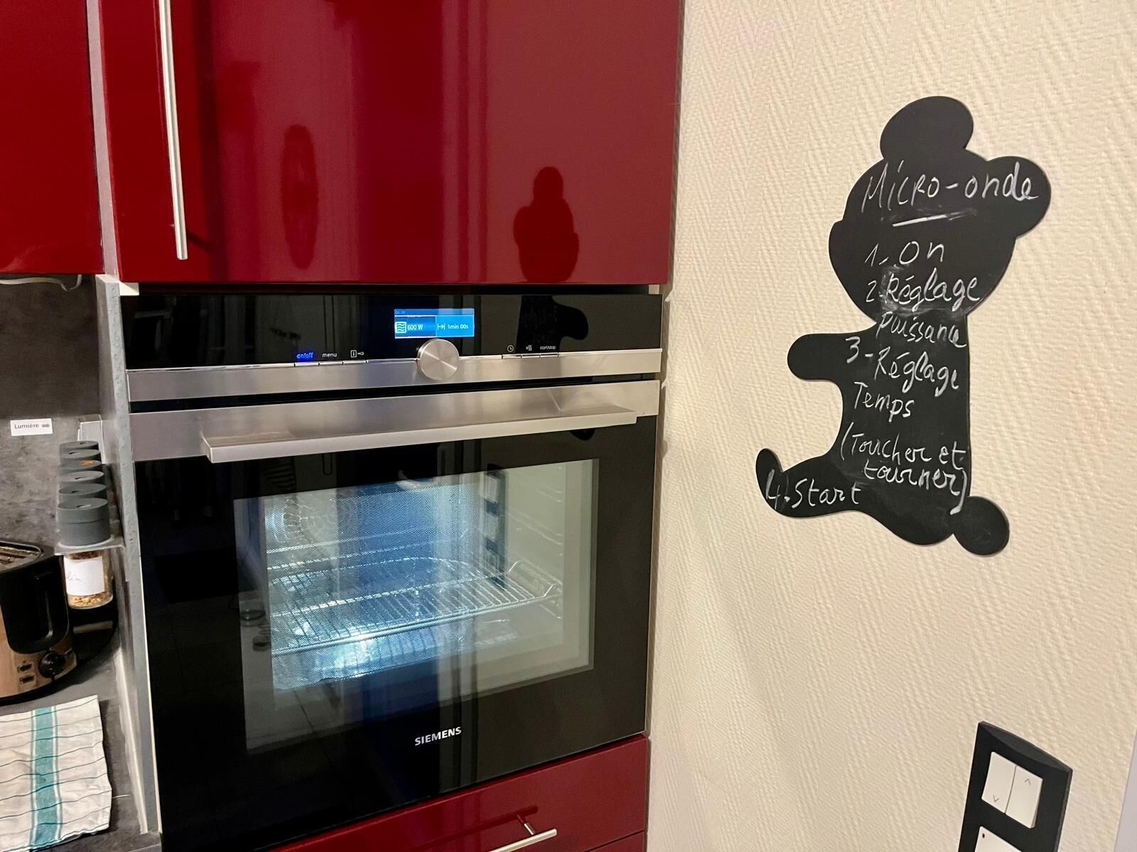 Una cocina con horno Siemens, pantalla digital y una pared con menú en pizarra.
