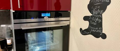 Una cocina con horno Siemens, pantalla digital y una pared con menú en pizarra.