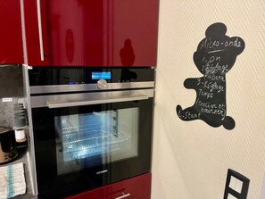 Una cocina con horno Siemens, pantalla digital y una pared con menú en pizarra.
