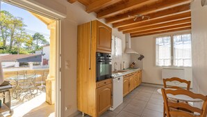 Una cocina con armarios de madera, lavavajillas y comedor con mesa y sillas.