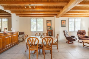 A dining area with a wooden table and chairs, a wooden cabinet, and two recliner chairs. - Bright Apartment 300m from the Beach (La Tremblade)